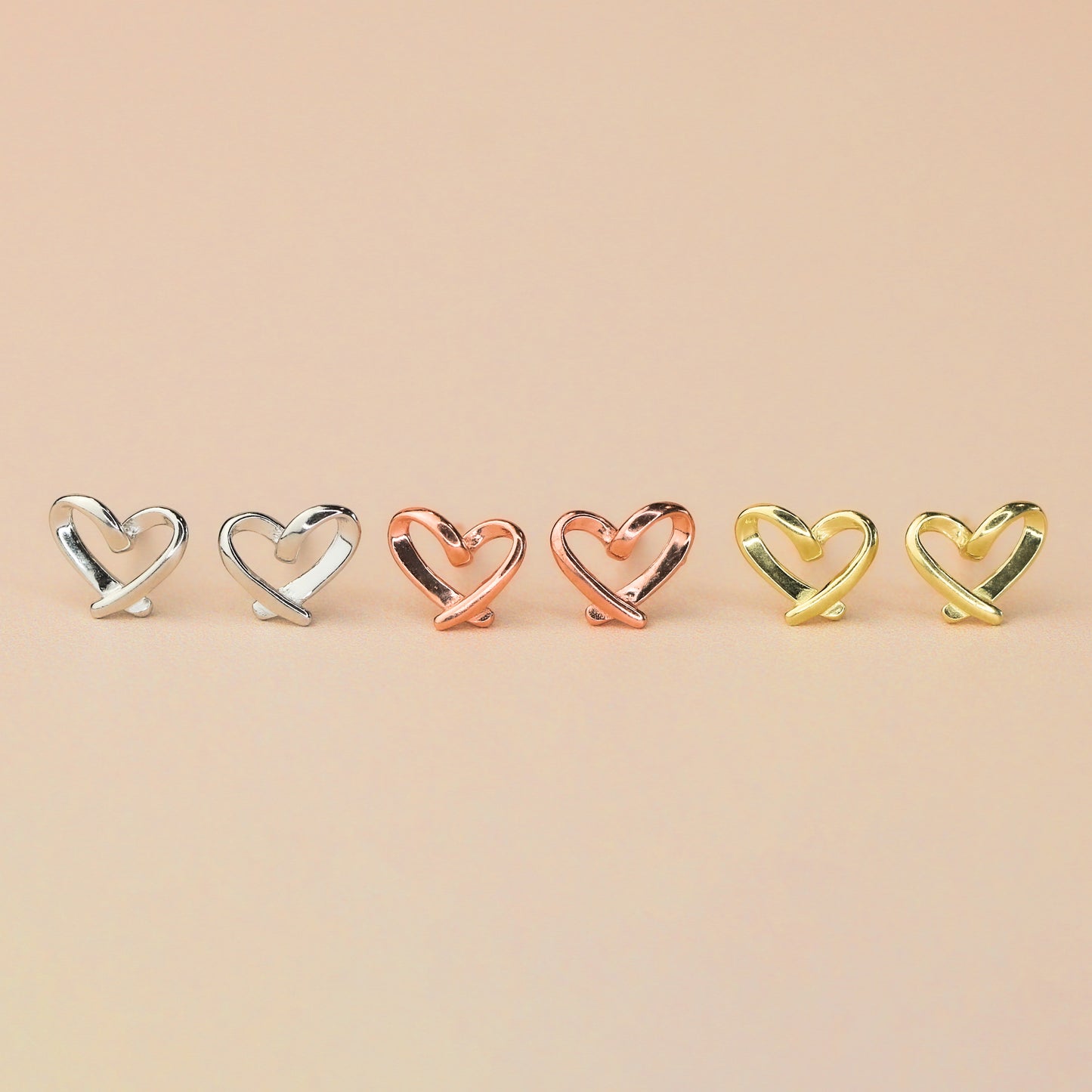 Three pairs of heart stud earrings, in silver, gold and rose gold colour