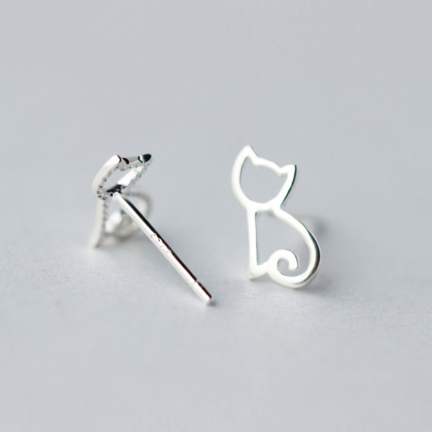 Silver stud earrings with a minimalist cat outline design