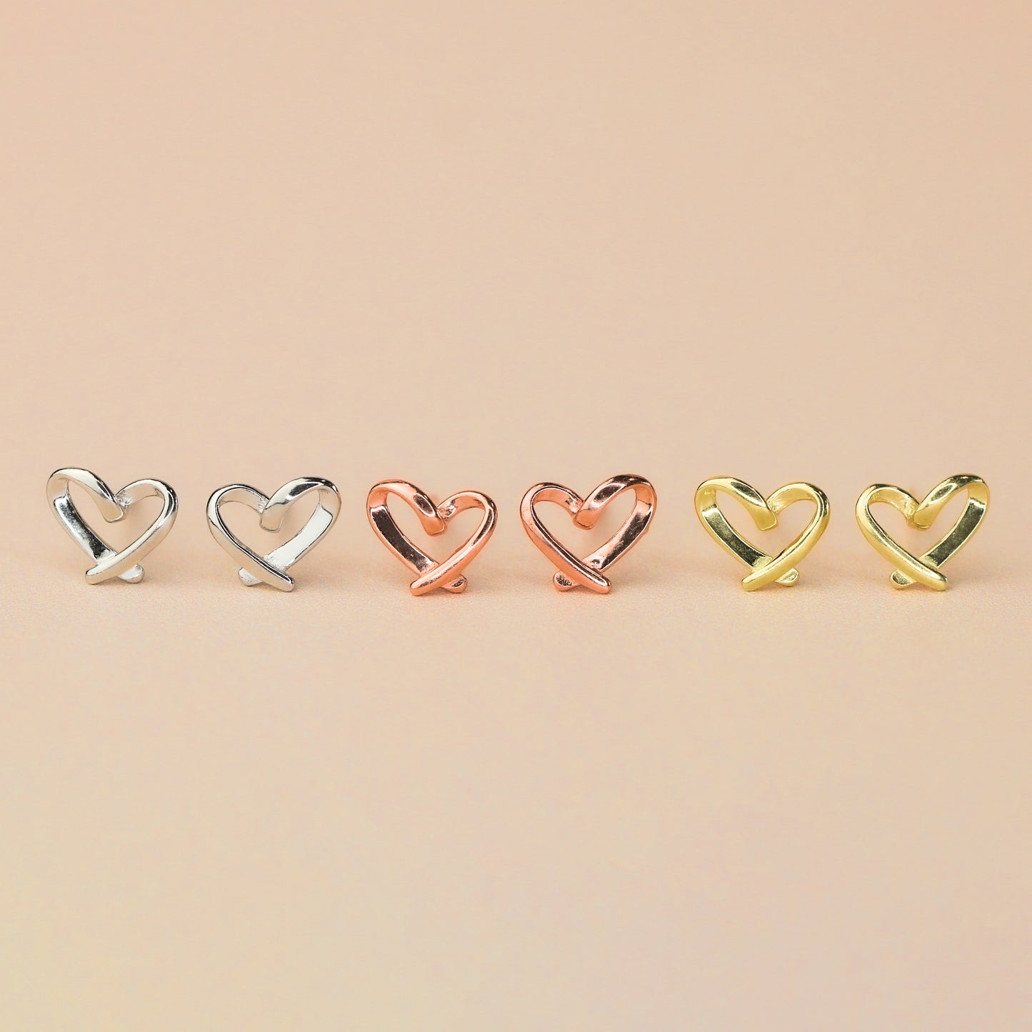 Three pairs of heart stud earrings, in silver, gold and rose gold colour