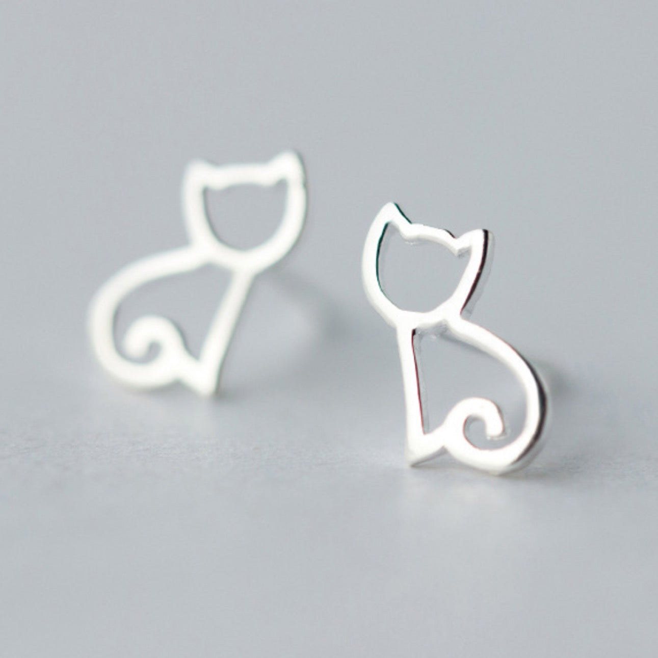 Silver stud earrings with a minimalist cat outline design
