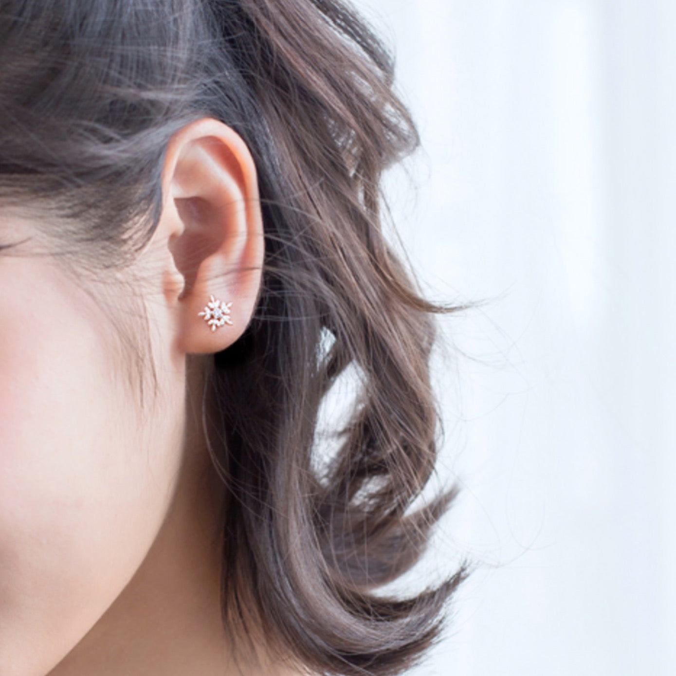 Model wearing silver snowflake earring.